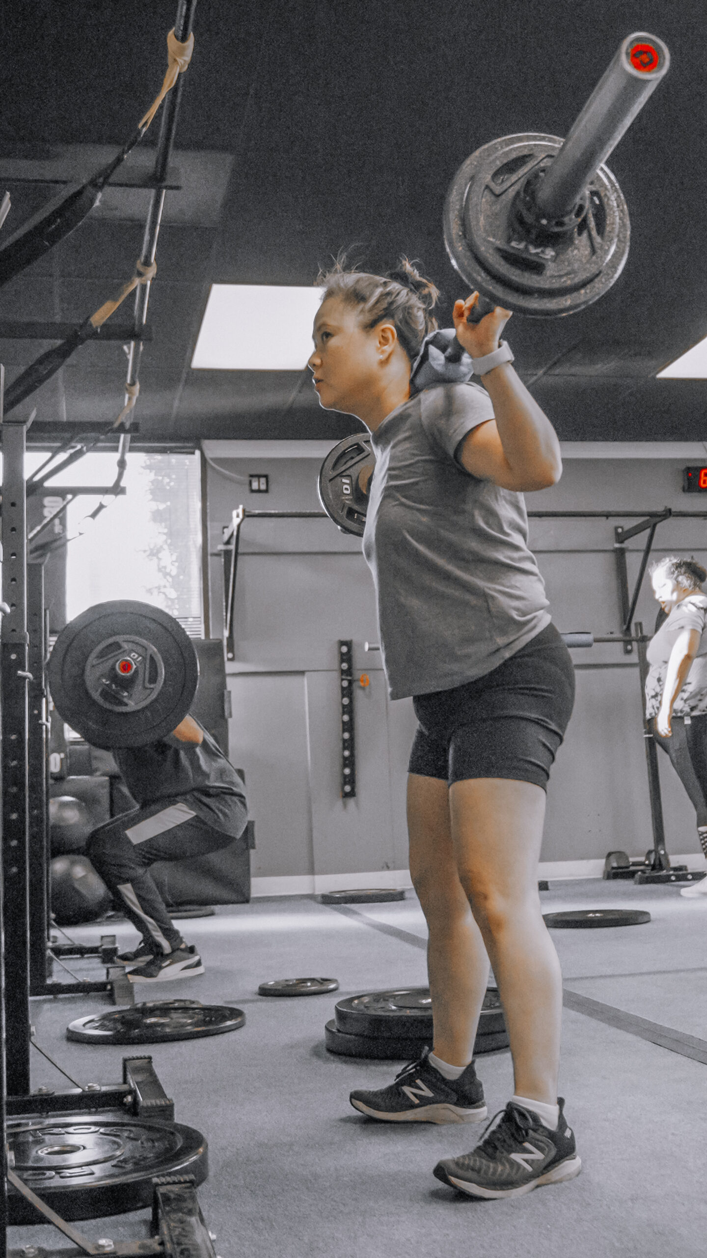 A woman doing squats with free weights at DNA Fitness during a workout session